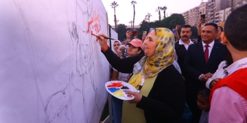 الوزيرة تكتب شعار المبادرة على الحائط التذكارى