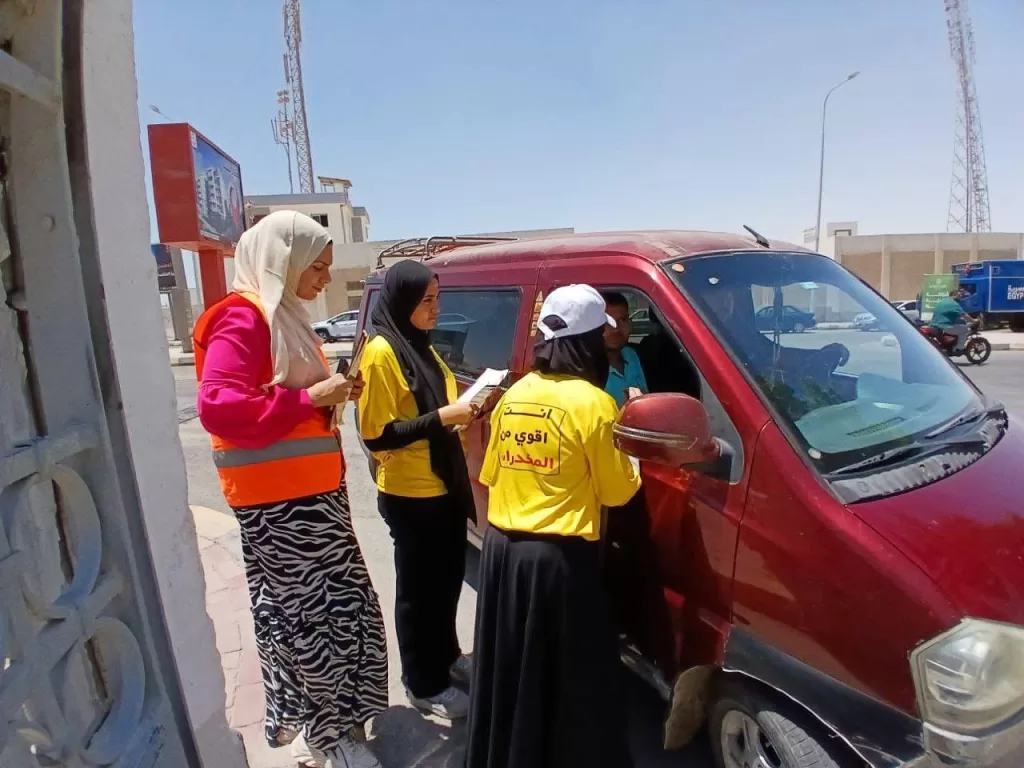 a group of women standing next to a red van